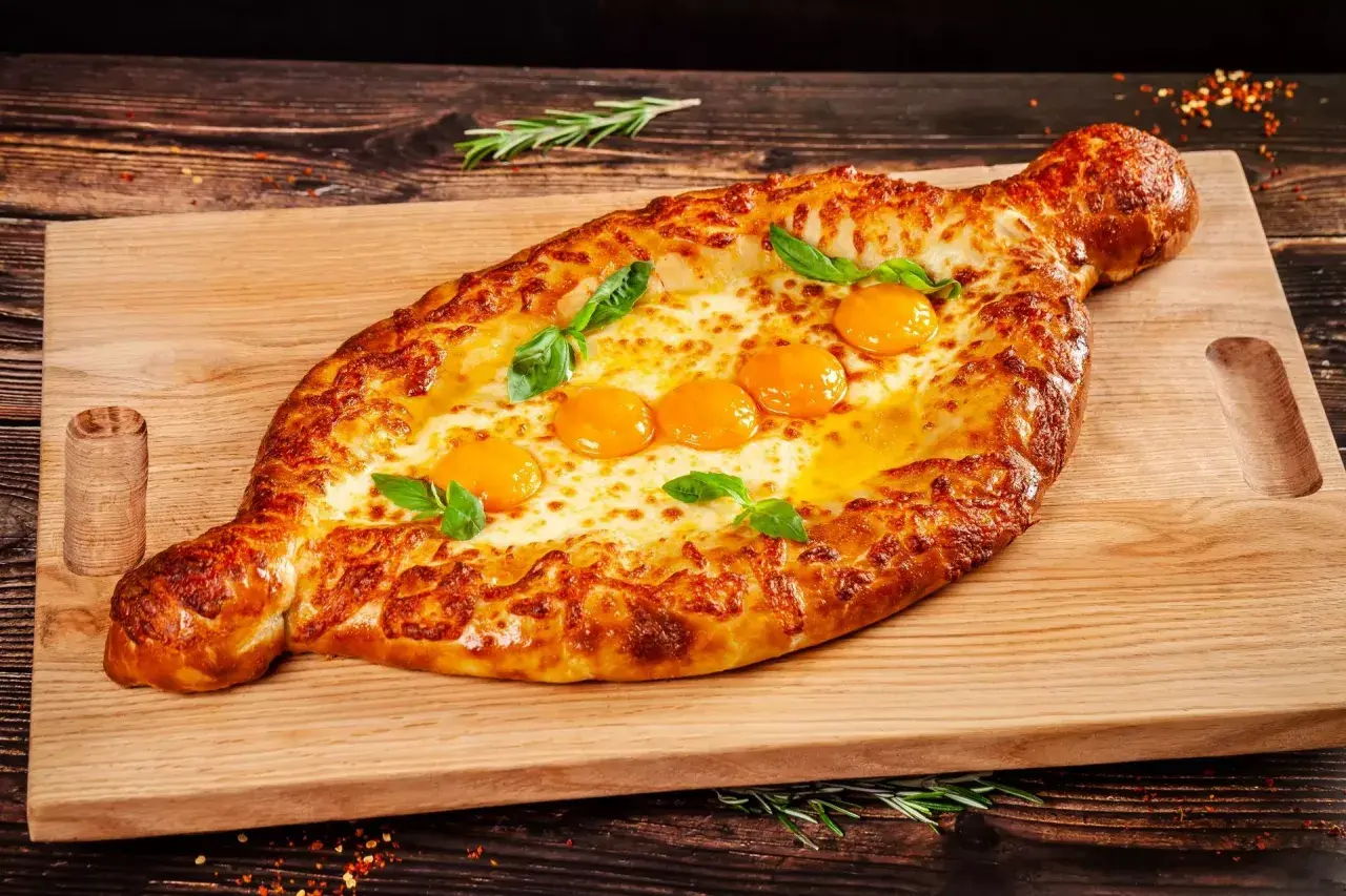 Chaczapuri adżarskie z rozpływającym się serem i jajkami, idealne na ucztę w restauracji gruzińskiej w Katowicach.
