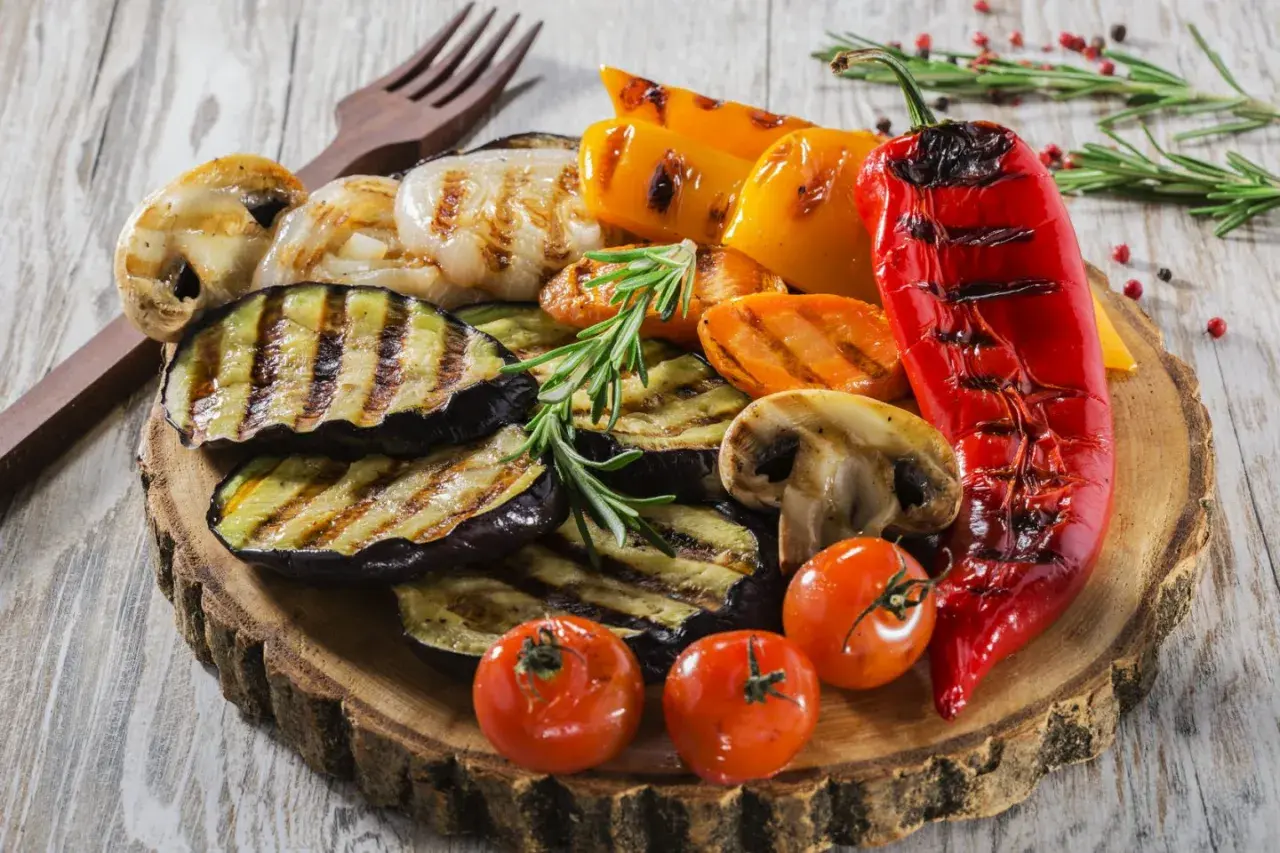 Pyszne przekąski na grilla: grillowany bakłażan, papryka, pieczarki, pomidorki i cebula, udekorowane rozmarynem.