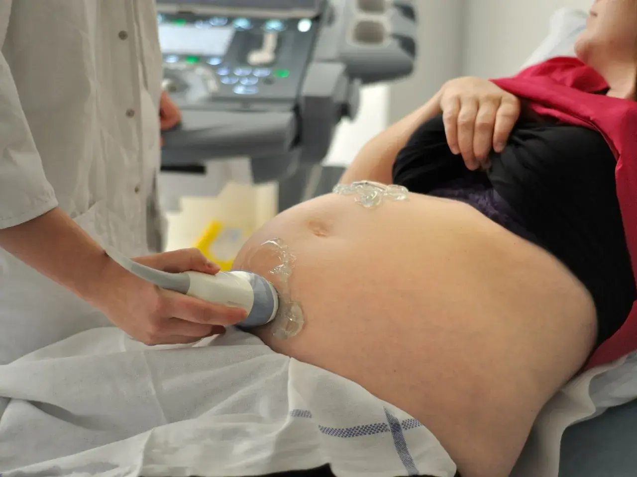 Eine Ärztin führt eine Ultraschalluntersuchung am Bauch einer Schwangeren durch. Die Frage, wie lange dauert eine schwangerschaft, wird hier bildlich beantwortet.