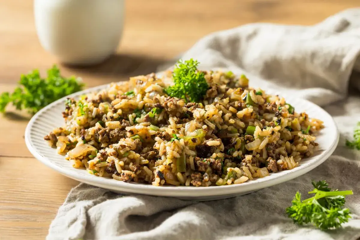Plato de arroz integral con carne molida y verduras, decorado con perejil fresco.