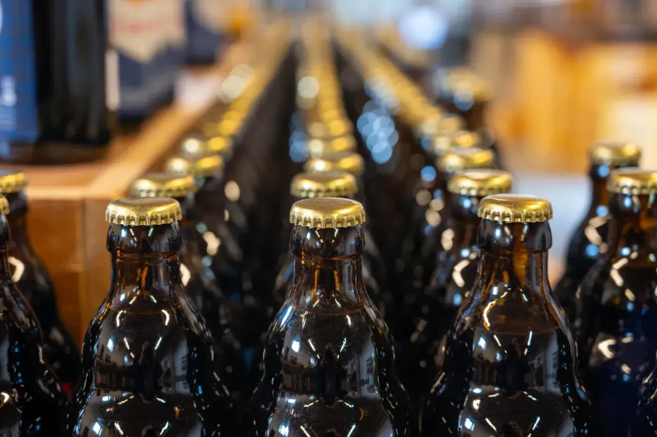 Rzędy ciemnych butelek z złotymi kapslami. Czy kwas chlebowy ma alkohol? To pytanie nurtuje wielu, a te butelki mogą zawierać odpowiedź.