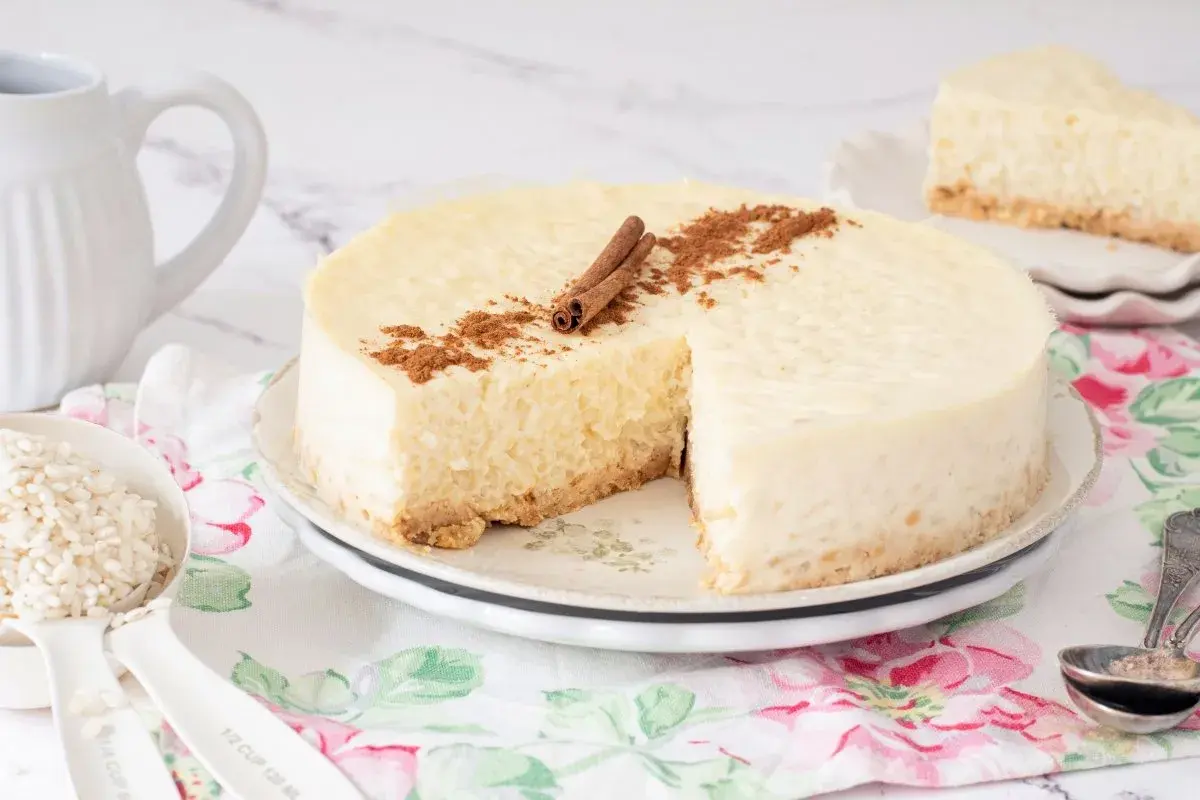 Deliciosa tarta de arroz cremosa, decorada con canela en rama y espolvoreada. Un trozo ya servido.