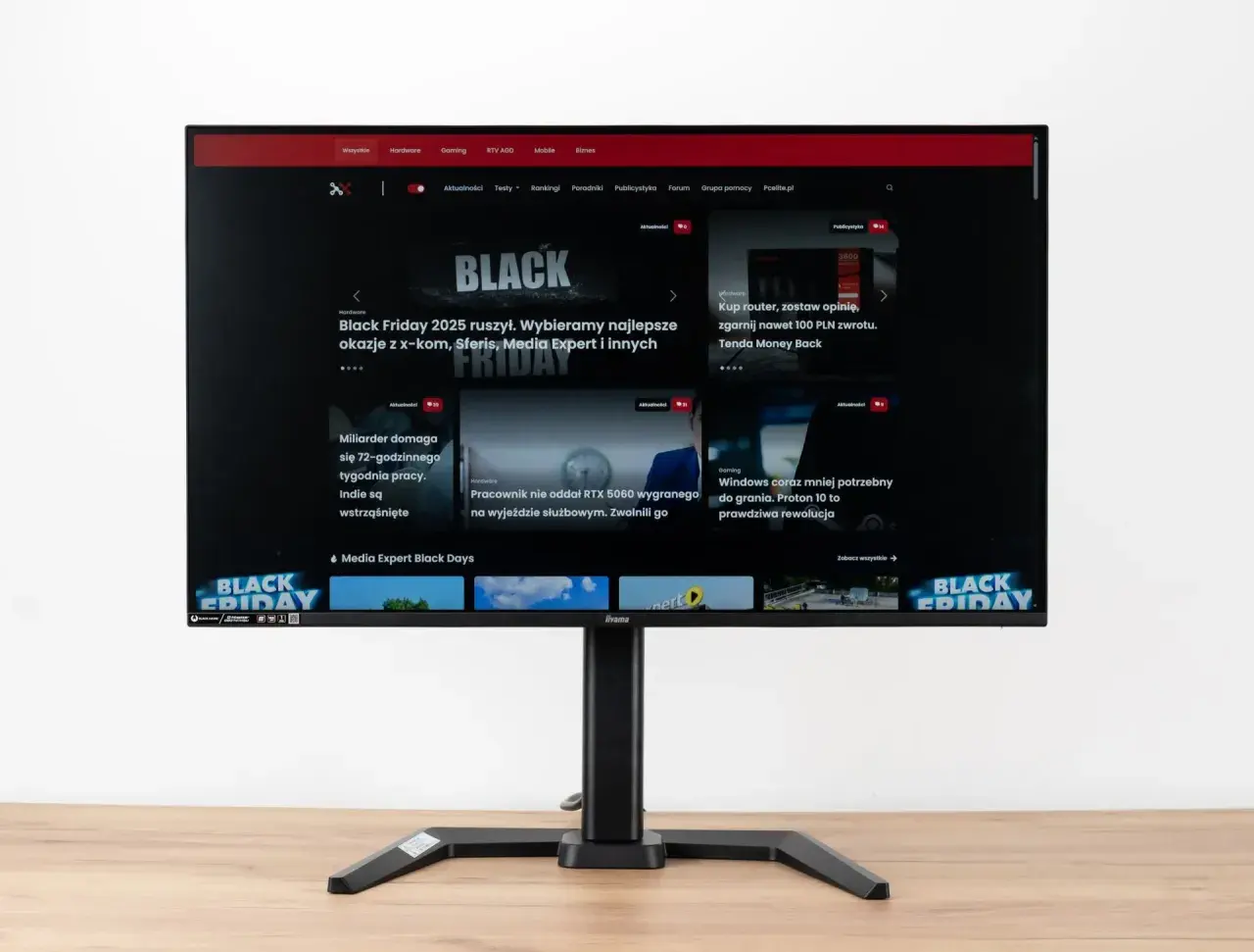 Monitor z widocznym na ekranie portalem Pcelite.pl, prezentującym artykuły o tematyce technologicznej, w tym promocje z okazji Black Friday. Test matrycy monitora jest kluczowy dla oceny jakości obrazu.