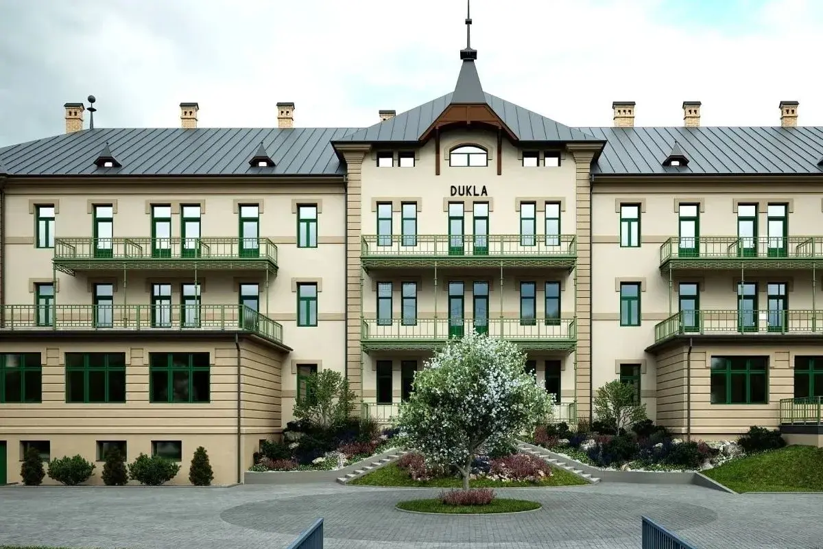 Elegancki budynek DUKLA z zielonymi balkonami i drzewkiem przed wejściem. Sprawdź bardejowskie termy cennik i zaplanuj relaks.