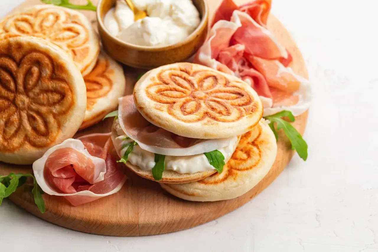 Tavola con crescentine, affettati e formaggio cremoso, un assaggio dei piatti tipici bolognesi.