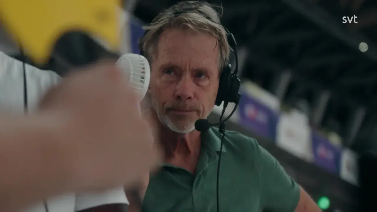 En svt sport medarbetare med headset och mikrofon, redo att rapportera från en sportarena.
