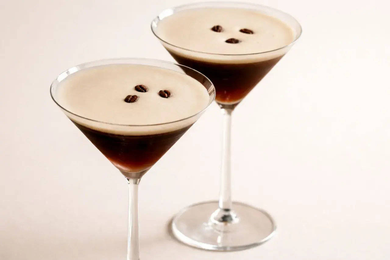 Zwei elegante Espresso Martini Gläser mit cremigem Schaum und Kaffeebohnen.