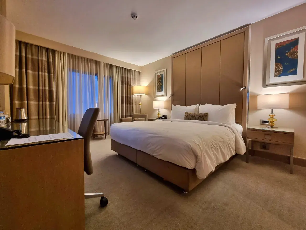 Komfortowy pokój hotelowy, idealny po długim locie tureckimi liniami lotniczymi. Duże łóżko, biurko i przytulne oświetlenie.
