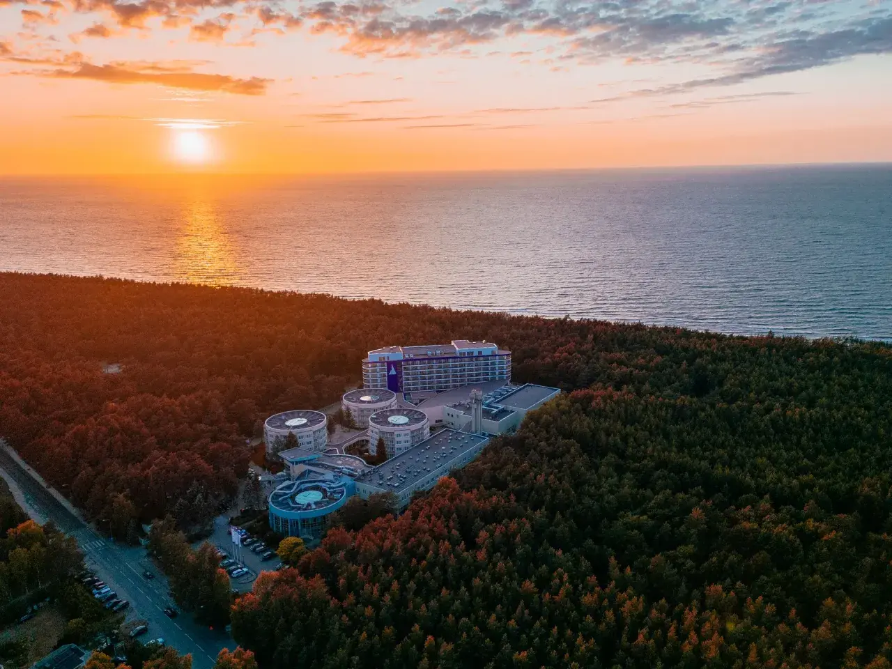 Zachód słońca nad morzem, otaczający las i kompleks hotelowy Hotel Senator Dźwirzyno.