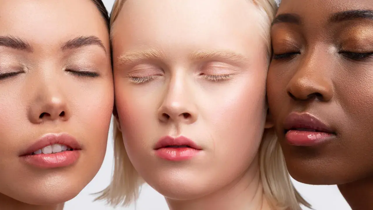 Trois visages aux teints variés, aux yeux clos, sublimés par un maquillage discret et naturel.