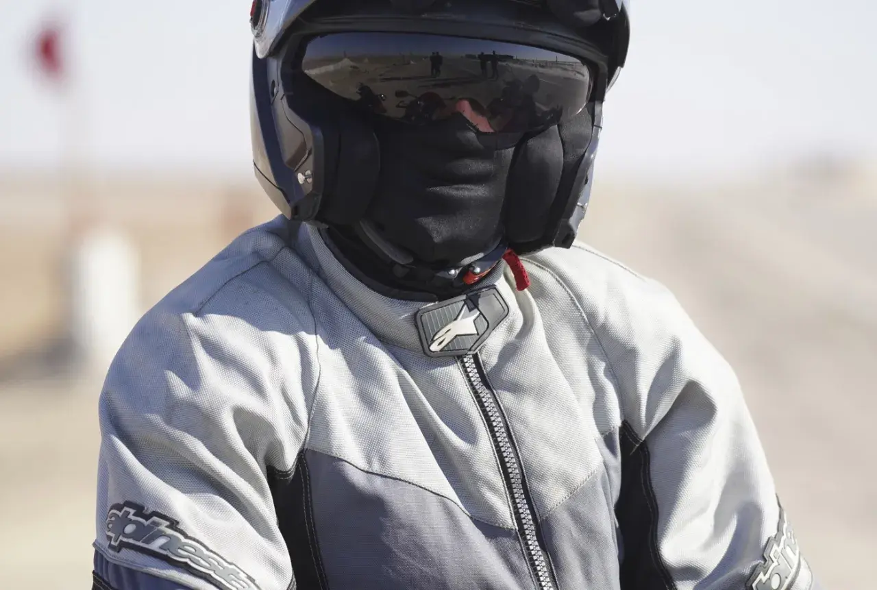 Motociclista con casco y pasamontañas, listo para viajar sin pasar frío en moto.