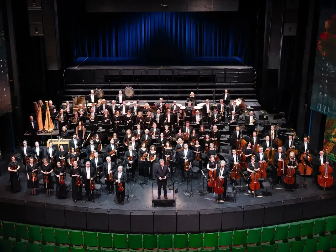 Wielka orkiestra symfoniczna na scenie, muzycy w strojach galowych, dyrygent. To właśnie opera co to za widowisko!