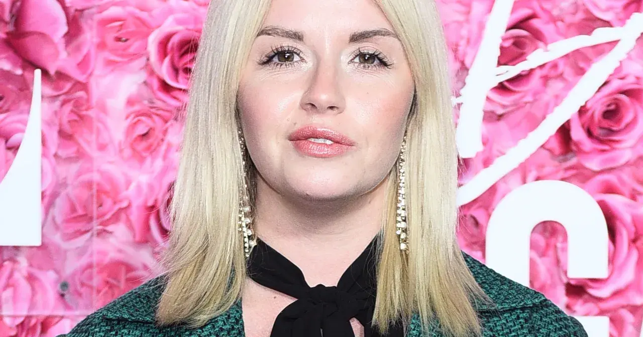 Agnieszka Wolszczyk, wiek nieznany, na tle różowych róż. Długie blond włosy, błyszczące kolczyki.