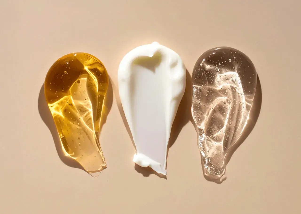 Tre olika krämsvansar: en gyllene olja, en vit kräm och en klar gel. Kanske en innehåller retinol, vitamin A för hudvård.
