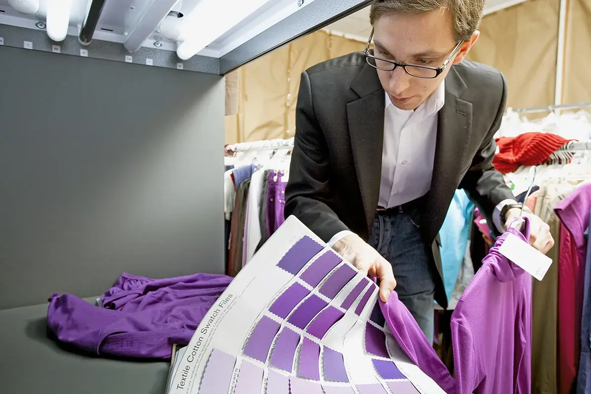 Un ingénieur textile examine des échantillons de couleurs violettes, comparant une chemise à un nuancier.
