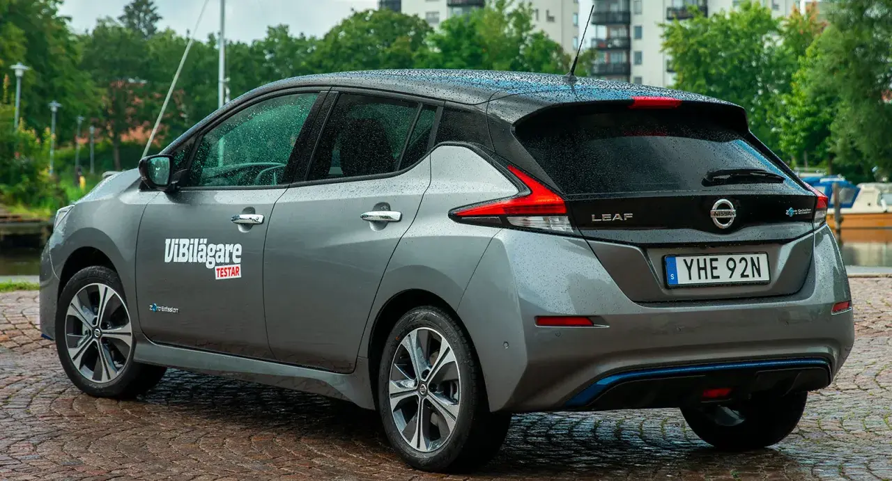 Grå Nissan Leaf med texten "ViBilägare TESTAR" på sidan. Bilen står vid en kaj, kanske med ett nissan leaf problem att undersöka.