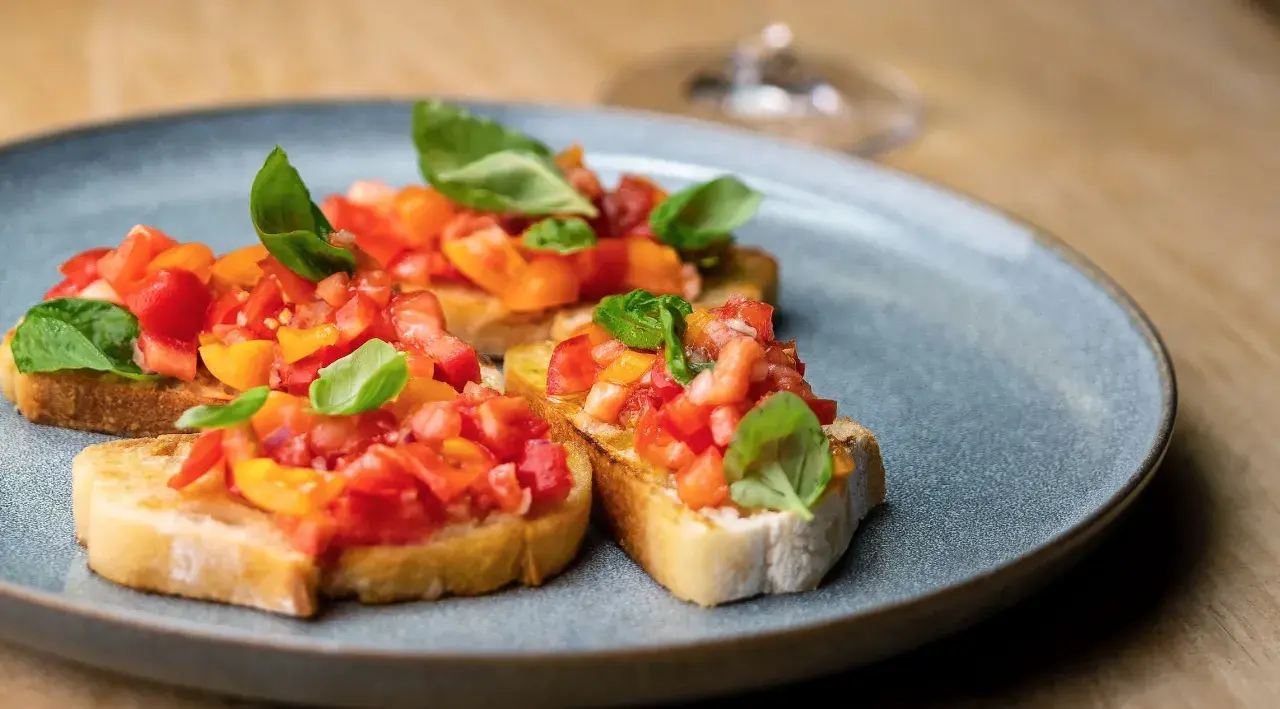 Bruschetta mit frischen Tomaten und Basilikum, ein klassisches rezept bruschetta original italienisch, auf einem grauen Teller serviert.