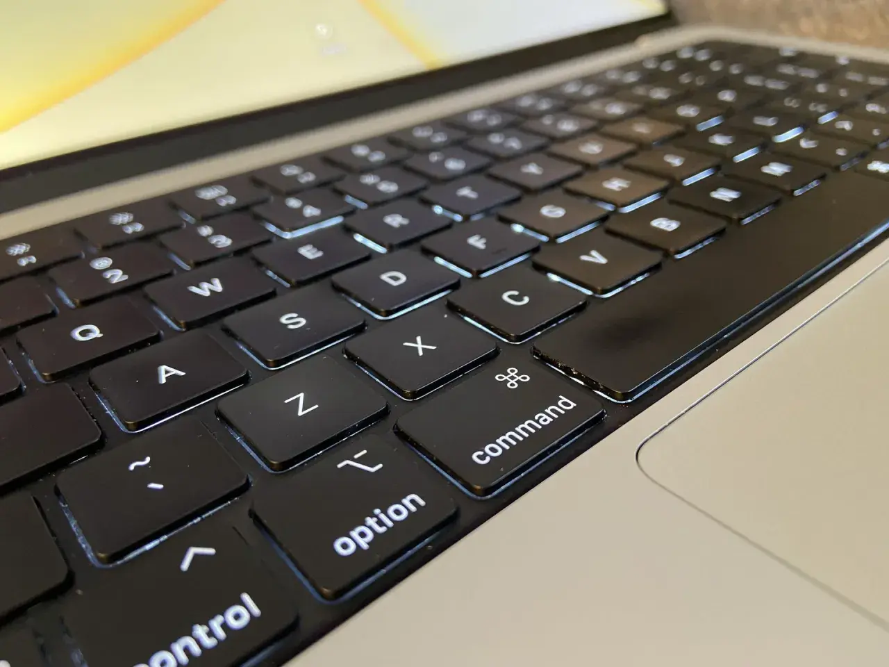 Klawiatura laptopa z podświetlanymi klawiszami. Widoczne litery Q, W, E, A, S, D, Z, X, C, a także klawisze "control", "option" i "command".