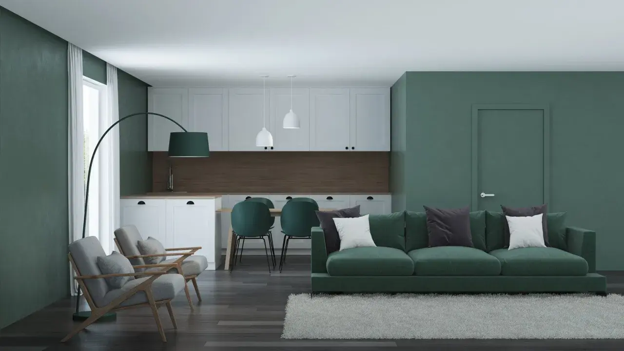 Nowoczesny salon z kuchnią, gdzie króluje **zielony kolor ścian**. Wygodna kanapa, fotele i krzesła tworzą przytulną przestrzeń.
