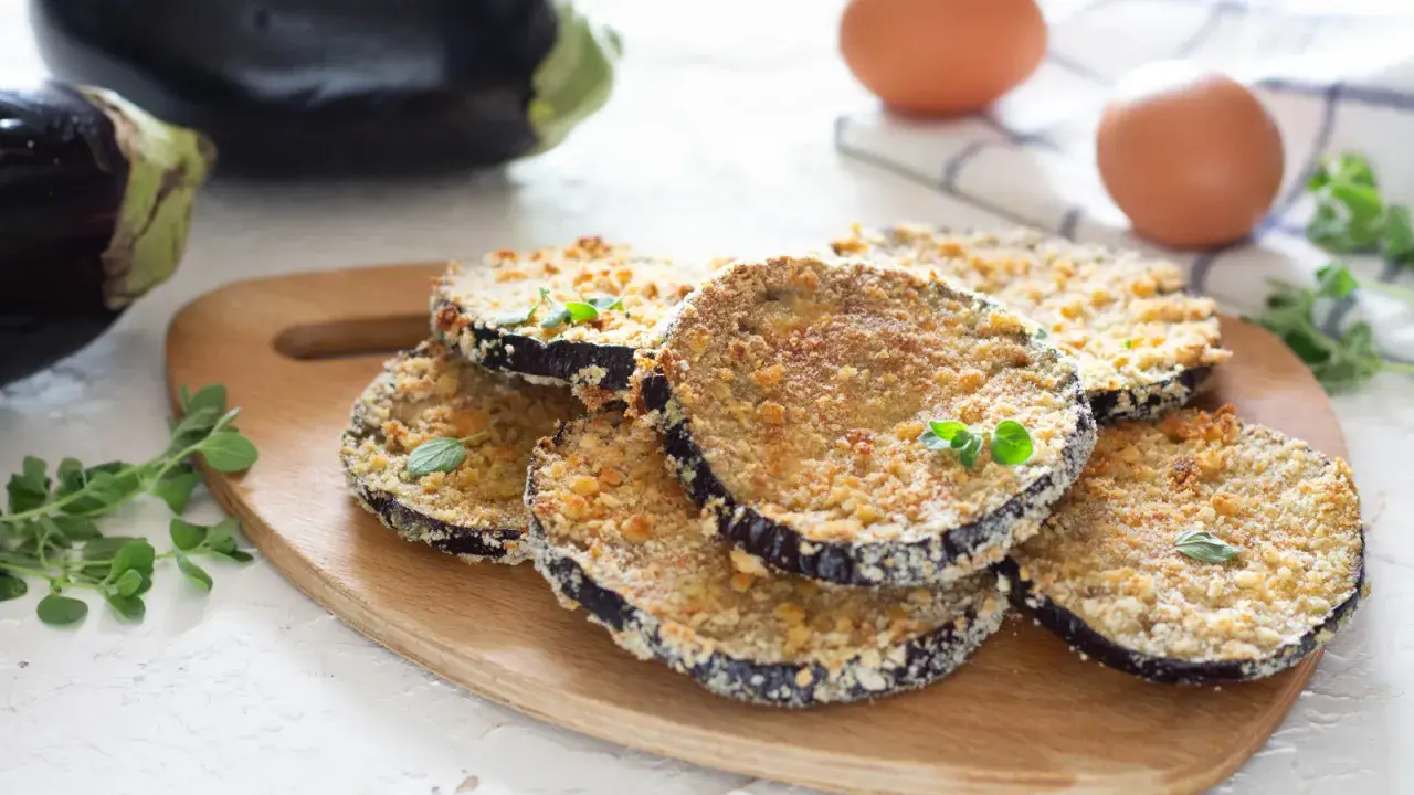 Cotolette di melanzane dorate e croccanti, guarnite con erbe aromatiche fresche, pronte per essere gustate.