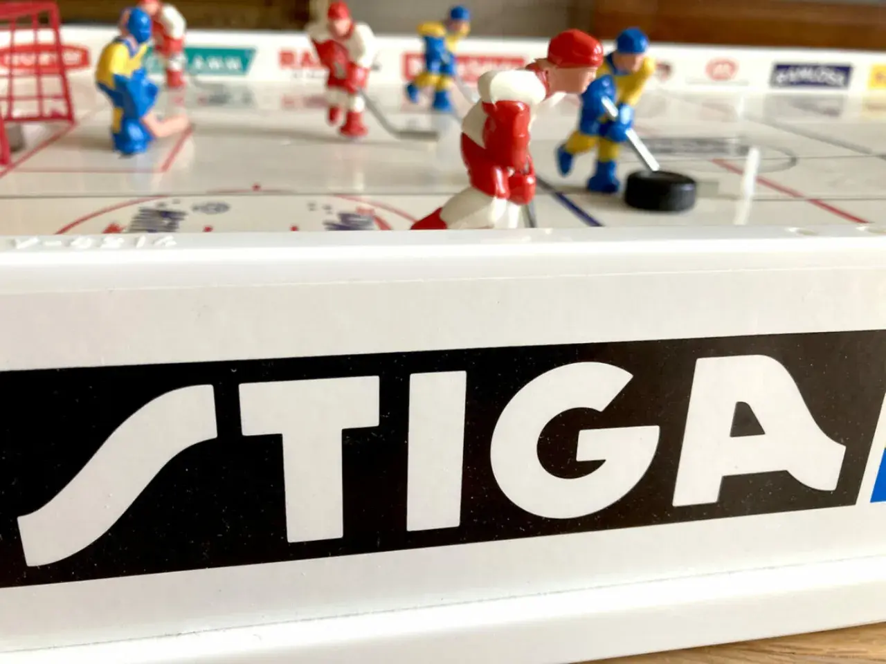 Stig Hjelmquist spelar hockey på STIGA-bordet. Röda och blå spelare kämpar om pucken på isen.