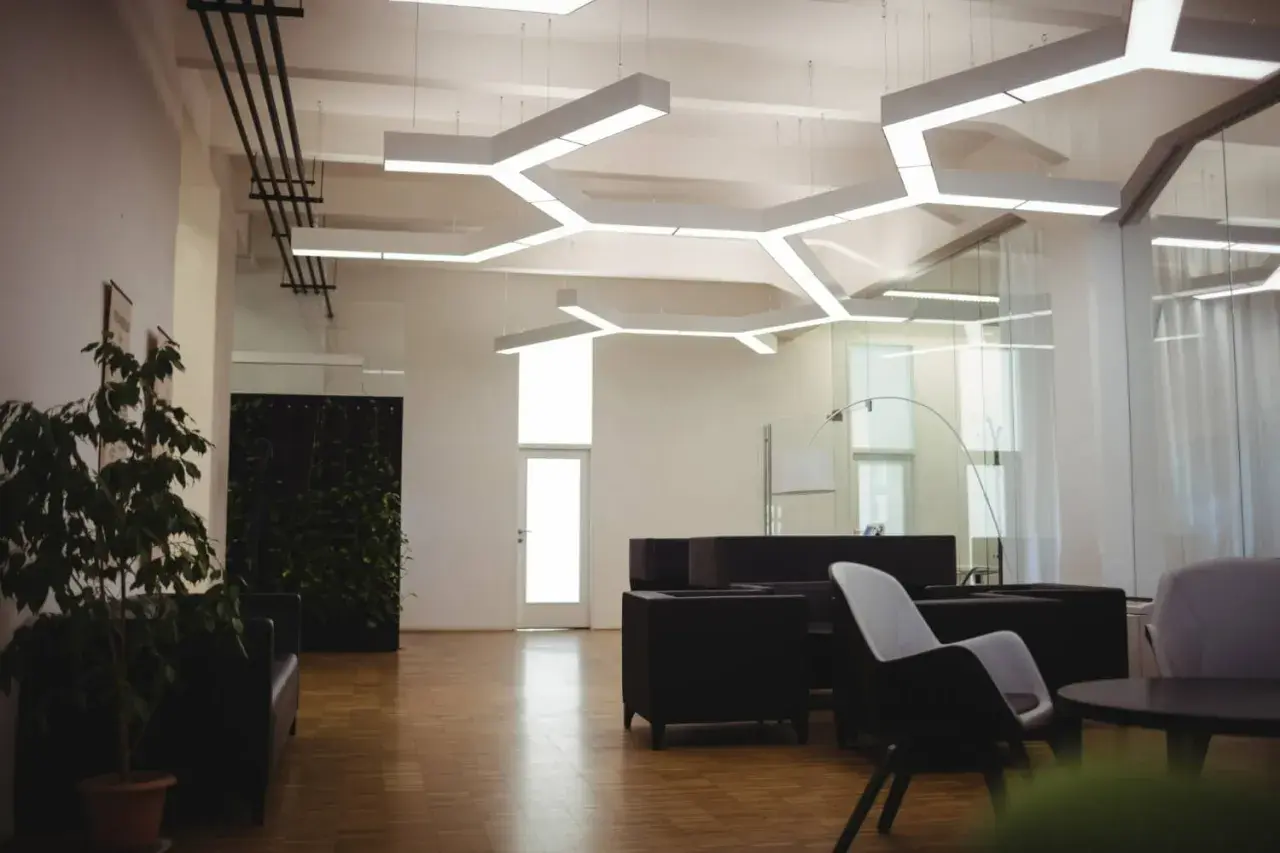 Nowoczesne biuro z designerskim oświetleniem. **LED zintegrowany co to znaczy?** To światło wbudowane w sufit, tworzące geometryczne wzory.
