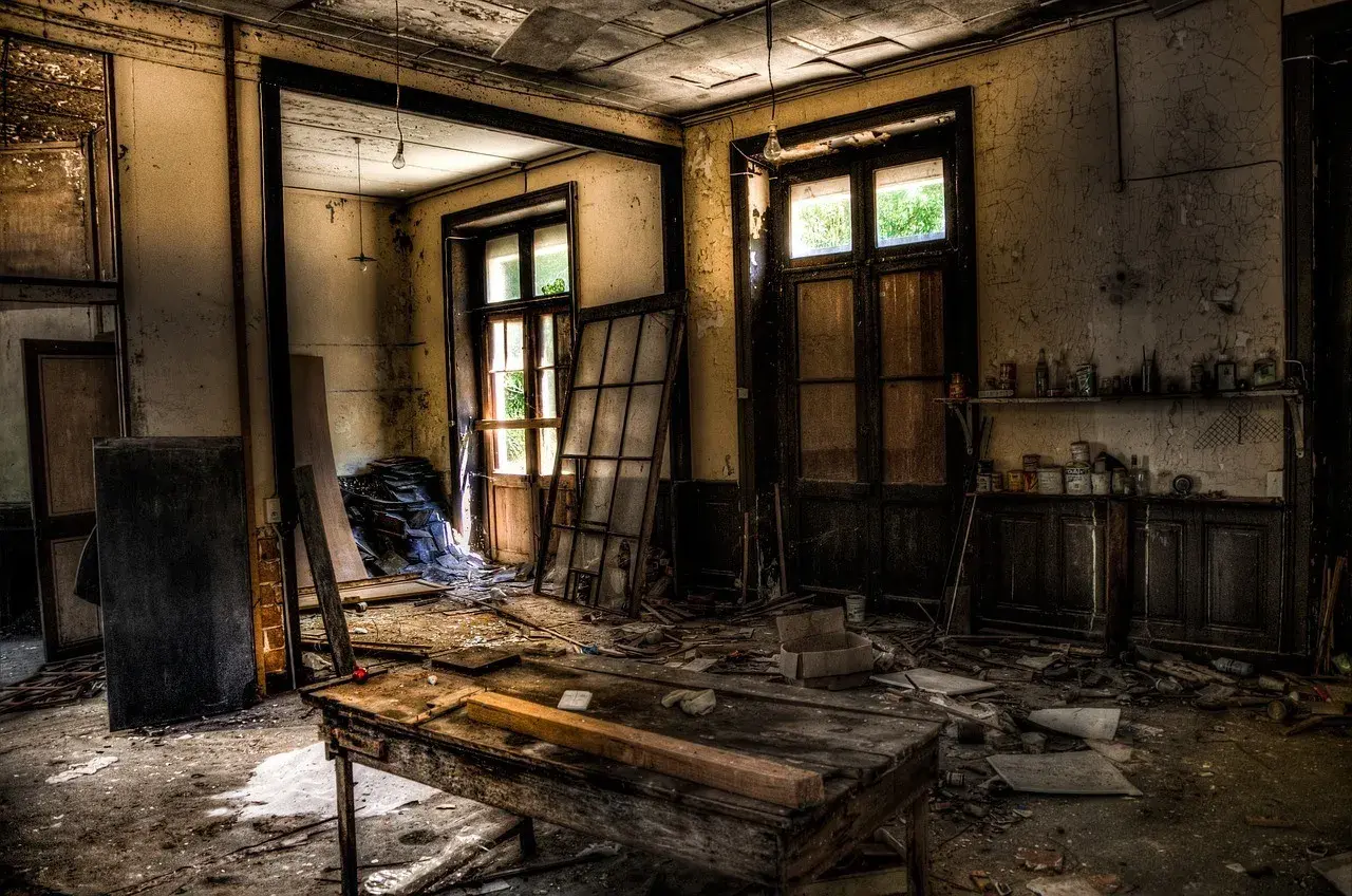 Intérieur d'un lieu abandonné en France. Un vieux bureau en bois trône au milieu des débris, sous des ampoules nues.