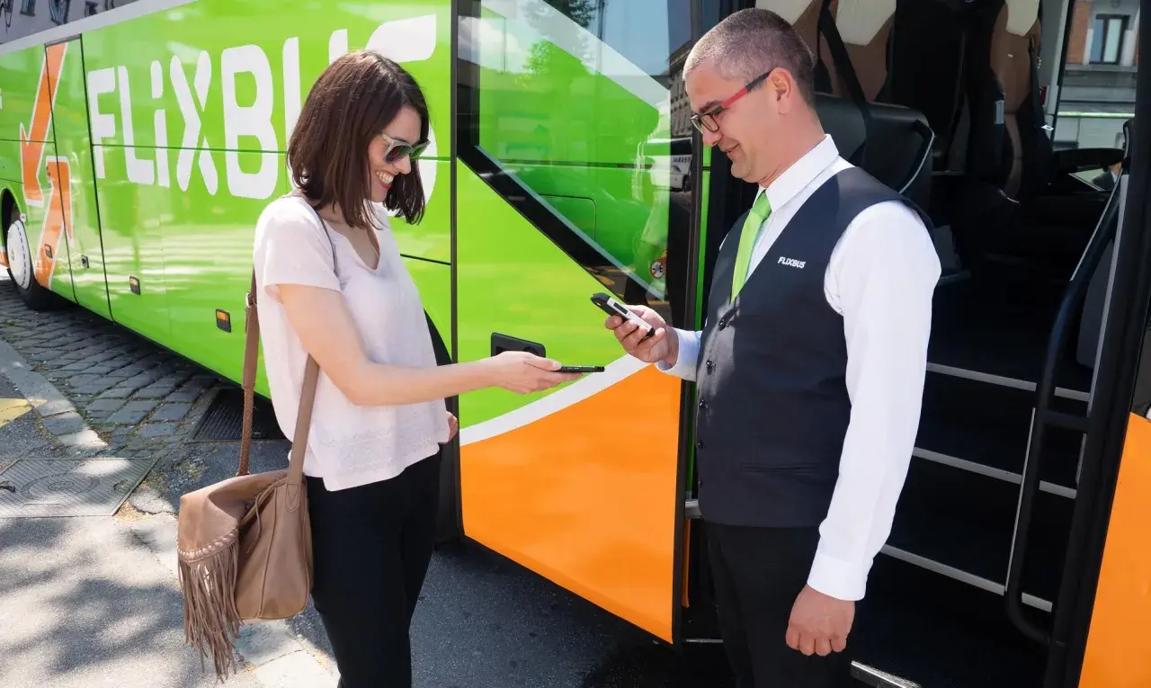 Kobieta pokazuje bilet na telefonie kierowcy Flixbus. Warto szukać flixbus promocje na podróże!