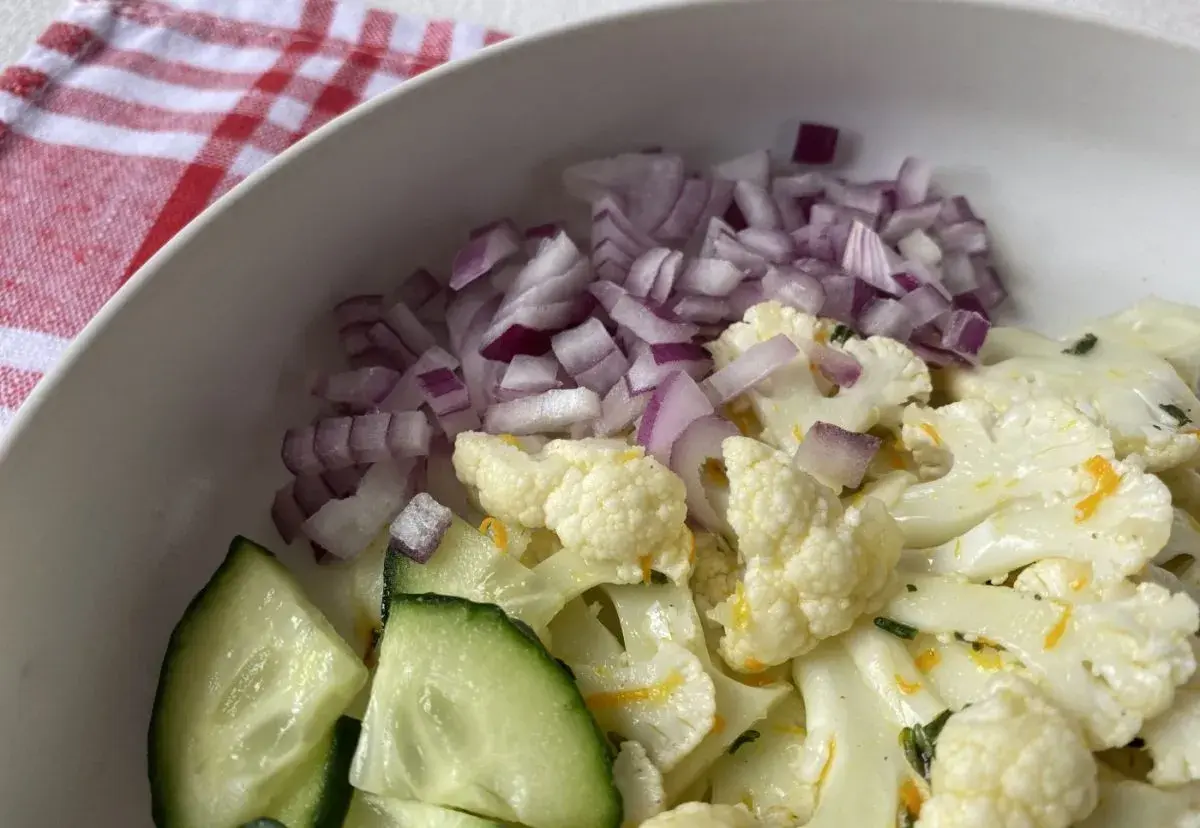 Ensalada de coliflor fresca con pepino y cebolla morada picada.