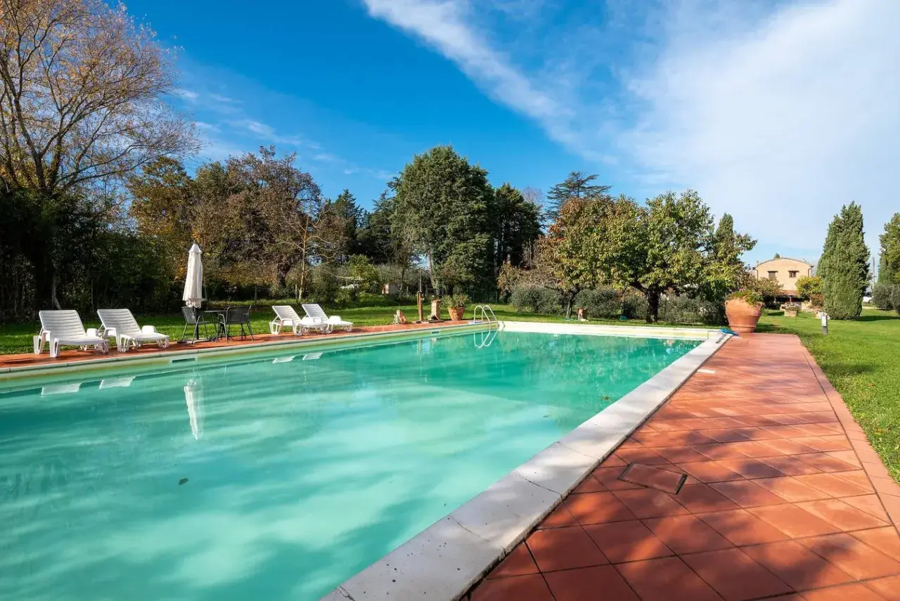 Piscine d'un gîte en Italie, entourée de verdure et de transats. Idéal pour des vacances paisibles.