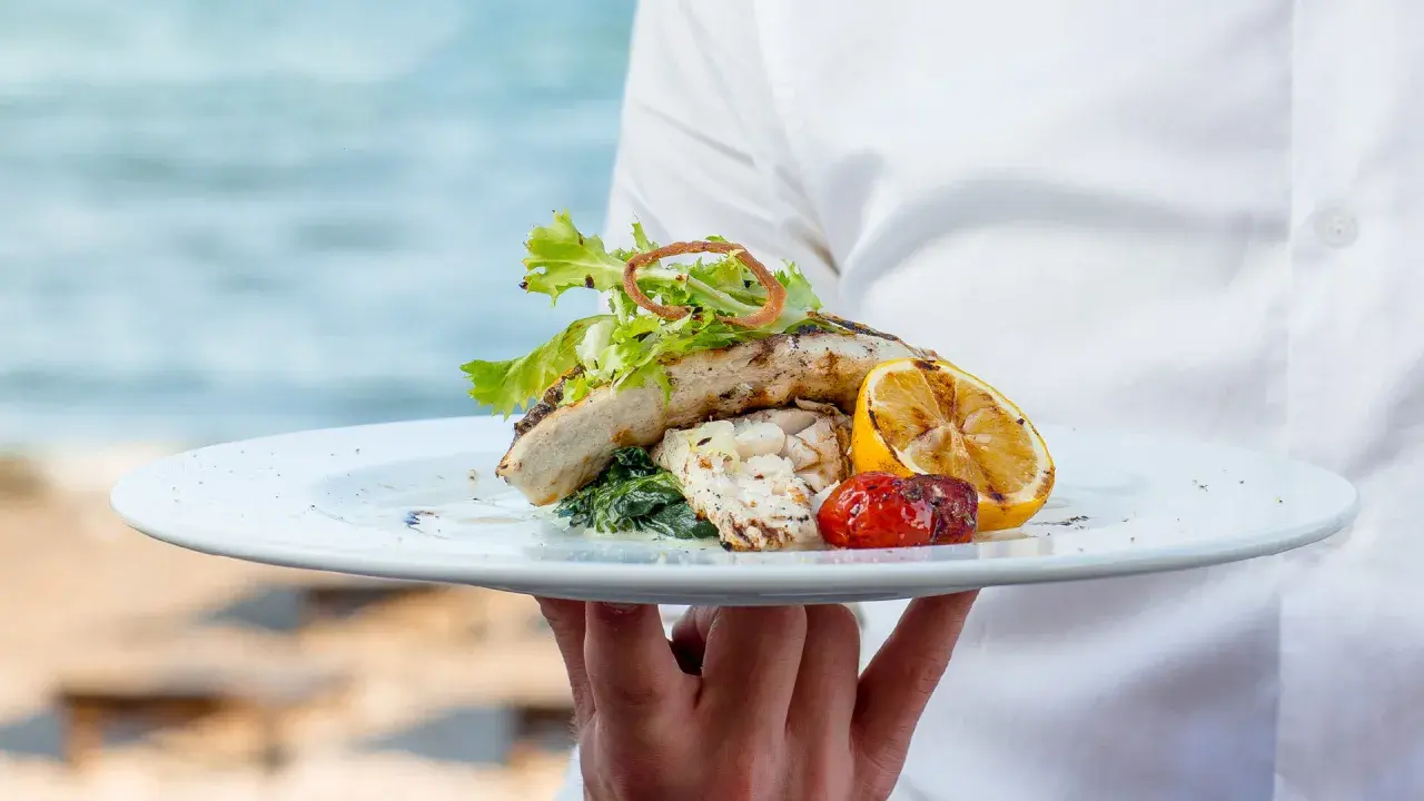 Delicioso plato de pescado a la parrilla con limón y tomate, servido en un restaurante en Cala Moraig.