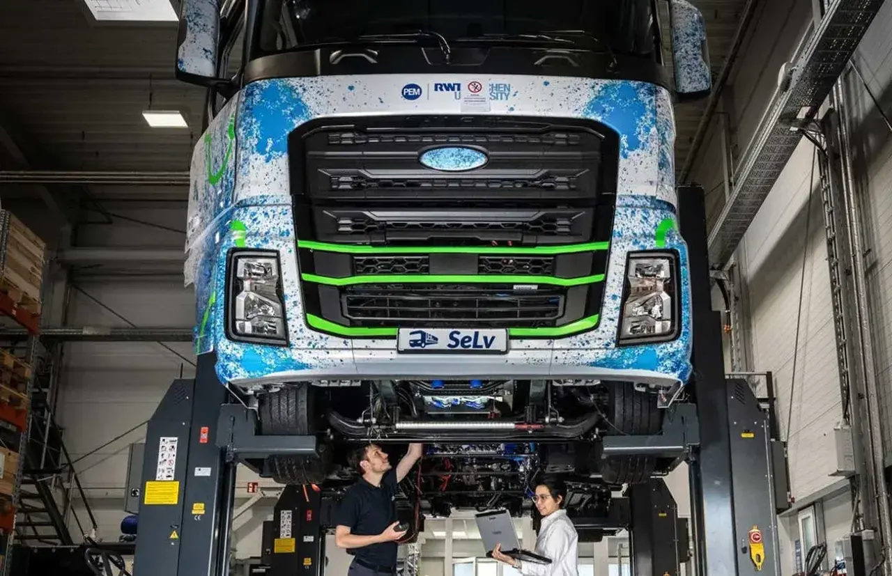Deux techniciens travaillent sur un camion diesel futuriste, explorant son autonomie et ses innovations.
