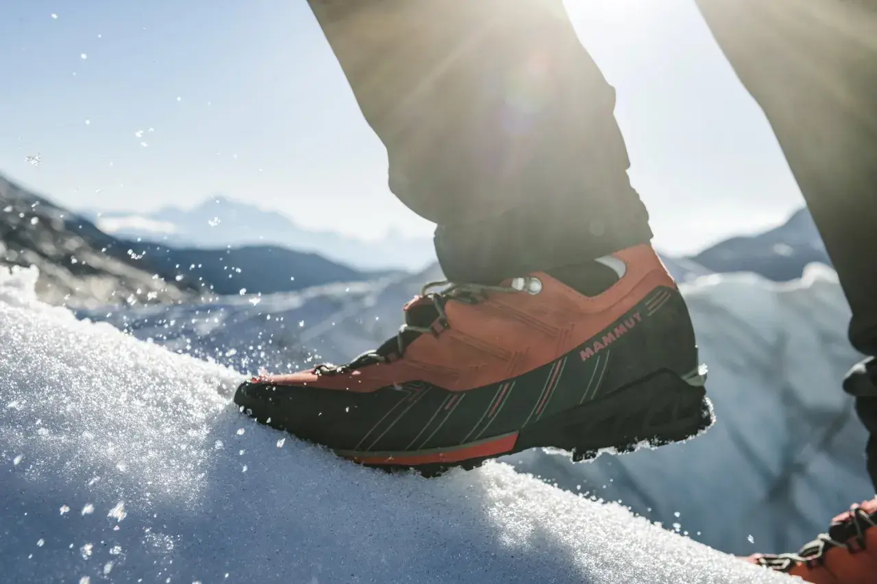 Pomarańczowe buty trekkingowe Mammut na śniegu, gotowe na wyprawę w Himalaje.