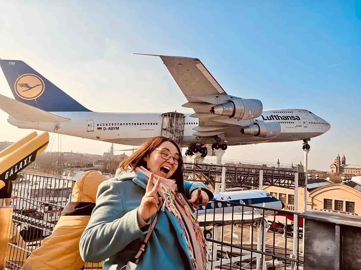Fröhliche Frau vor einem Jumbo-Jet im Technik Museum Speyer. Ein spannender Ausflug in die Welt der Luftfahrt.