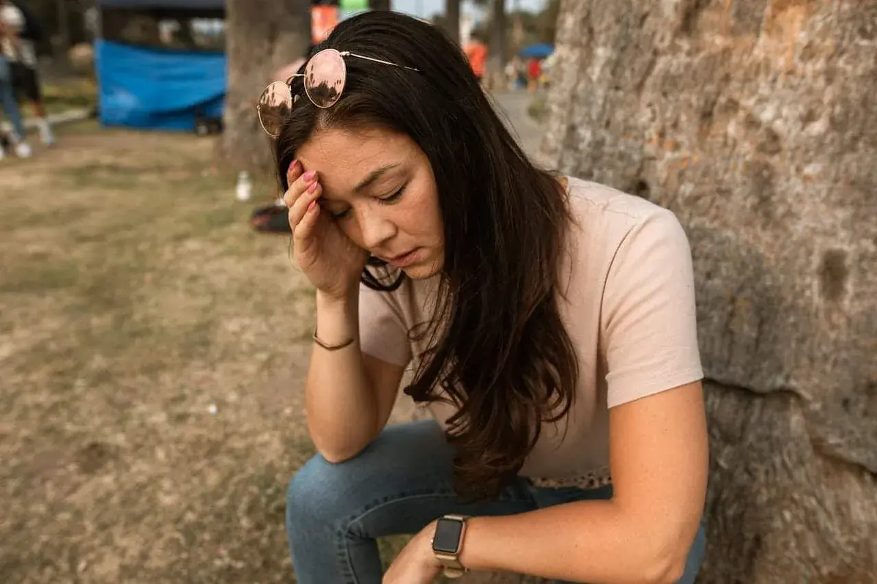 Vrouw met zonnebril op haar hoofd, hand op haar voorhoofd, lijkt te lijden aan een fobie voor naalden.