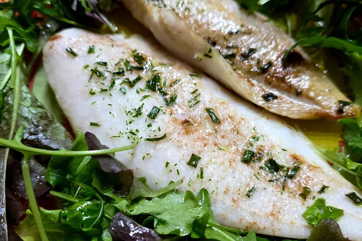 Delizioso merluzzo in friggitrice ad aria, cotto alla perfezione e servito su un letto di insalata fresca.