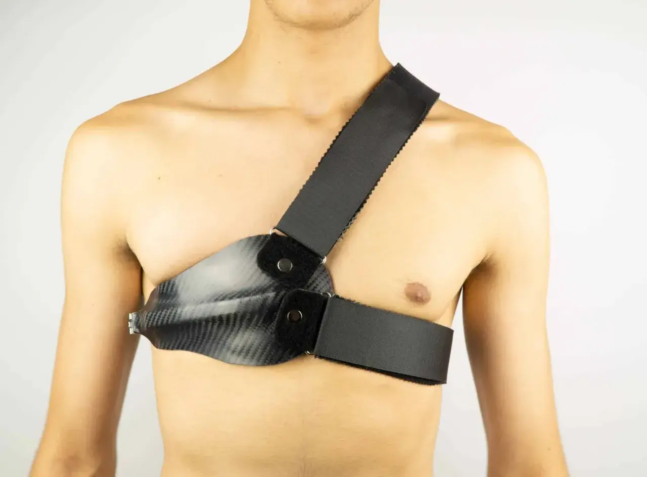 Person mit Carbon-Brustpanzer und Schultergurt. Der Rippenbuckel wird durch die Konstruktion gestützt.
