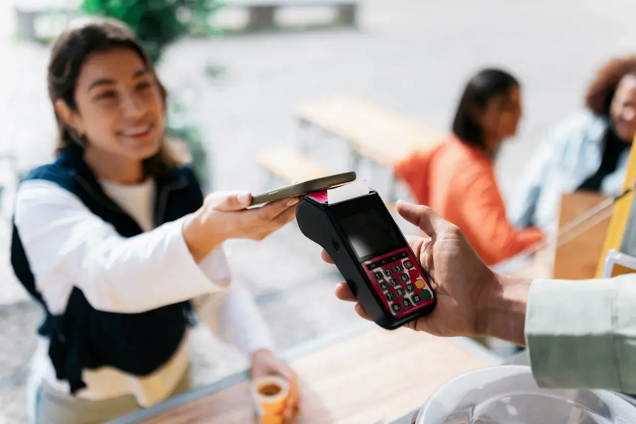 Junge Frau bezahlt kontaktlos mit ihrem Smartphone. Schnelle und einfache mobile payment Transaktion.
