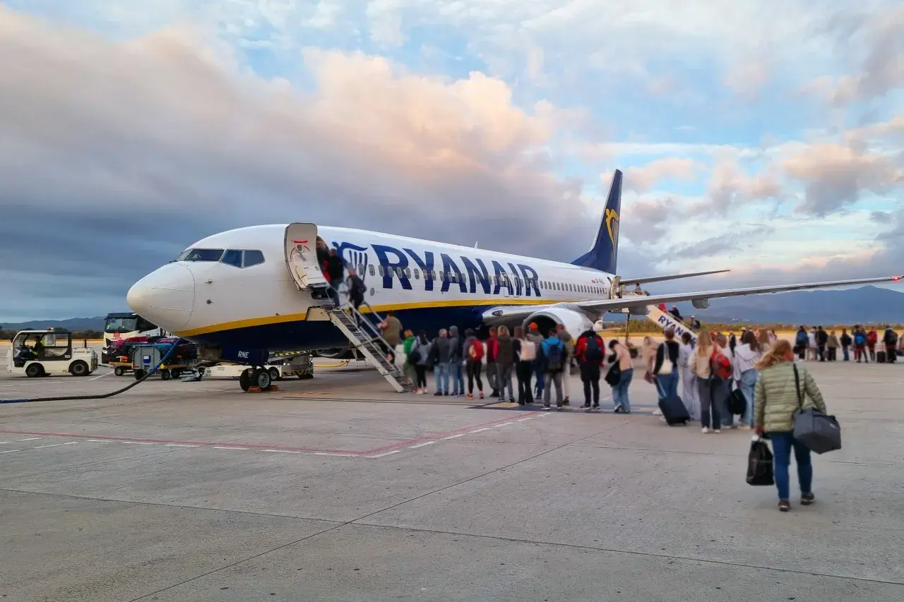 Pasażerowie wsiadają do samolotu Ryanair. W tle chmury i góry. To jak faktura za podróż, która właśnie się zaczyna.