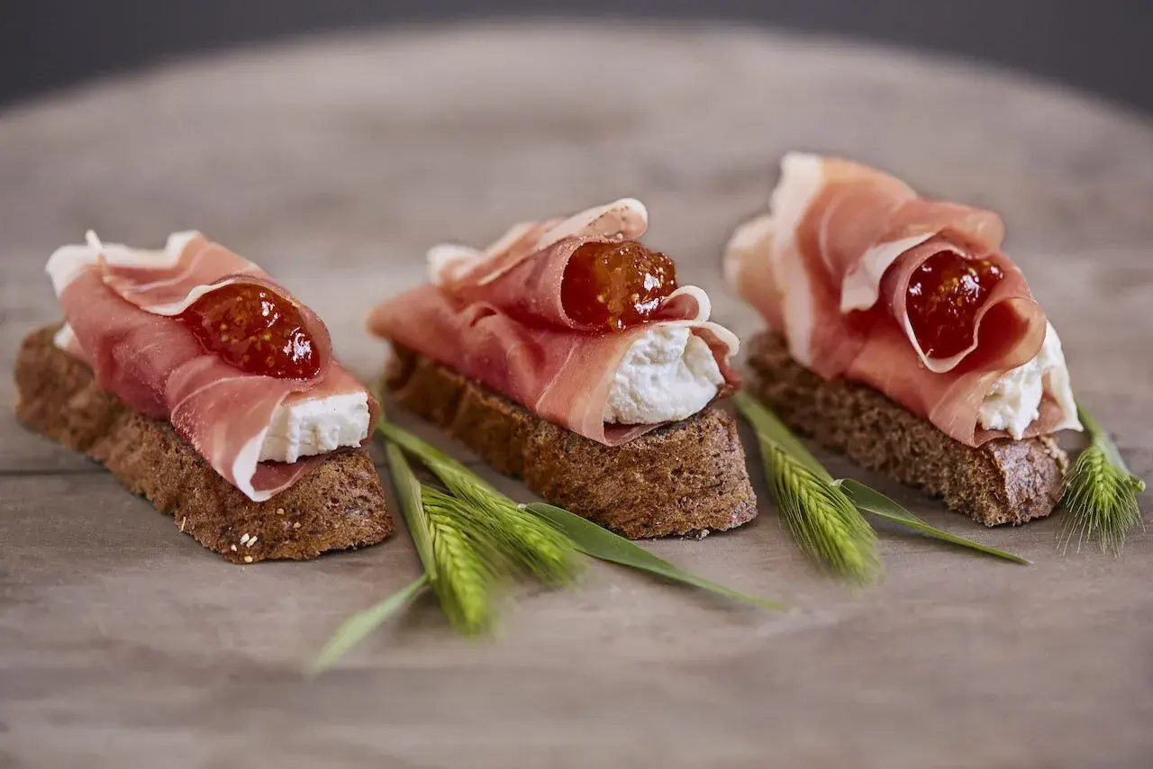 Drei kleine Brote mit Frischkäse, Feigenmarmelade und zartem **prosciutto schinken**.