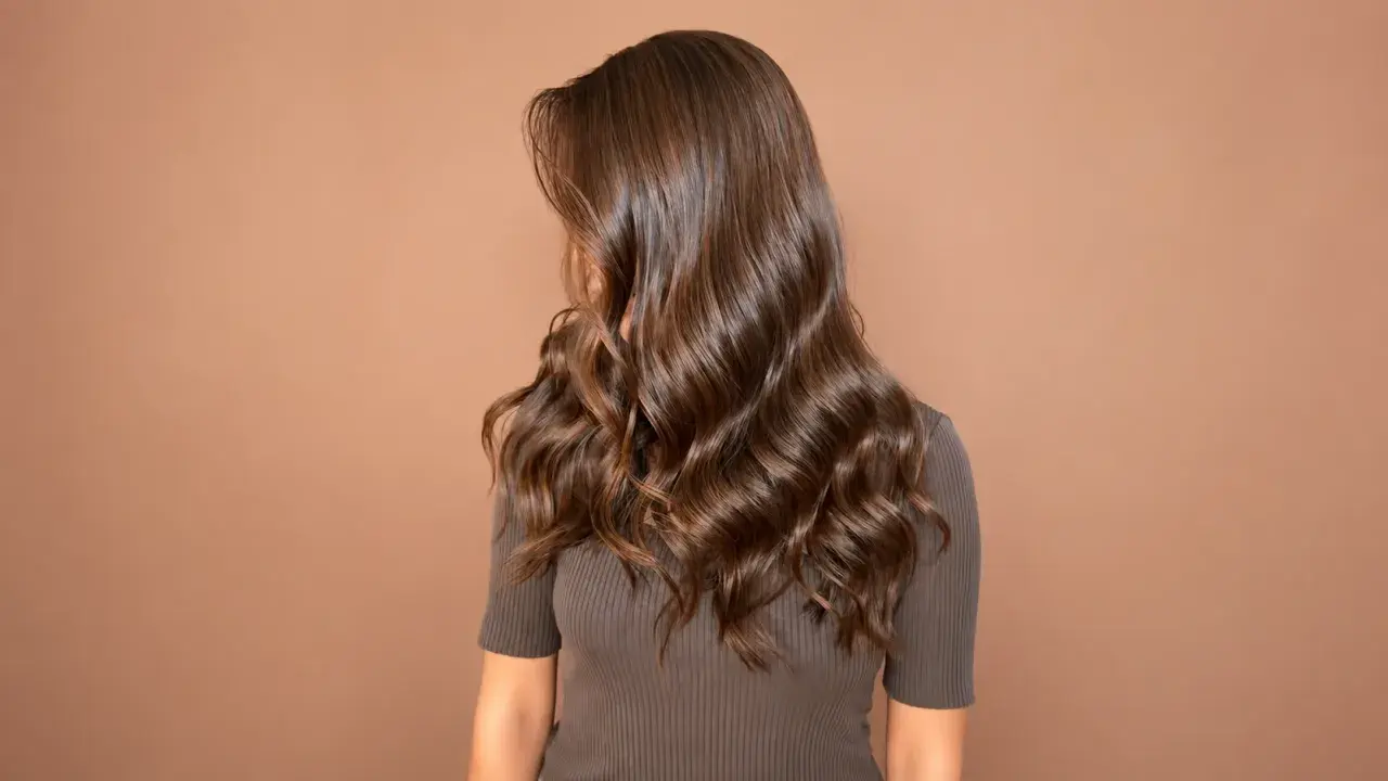 Melena larga y ondulada de color avellana pelo, con reflejos brillantes sobre fondo marrón.