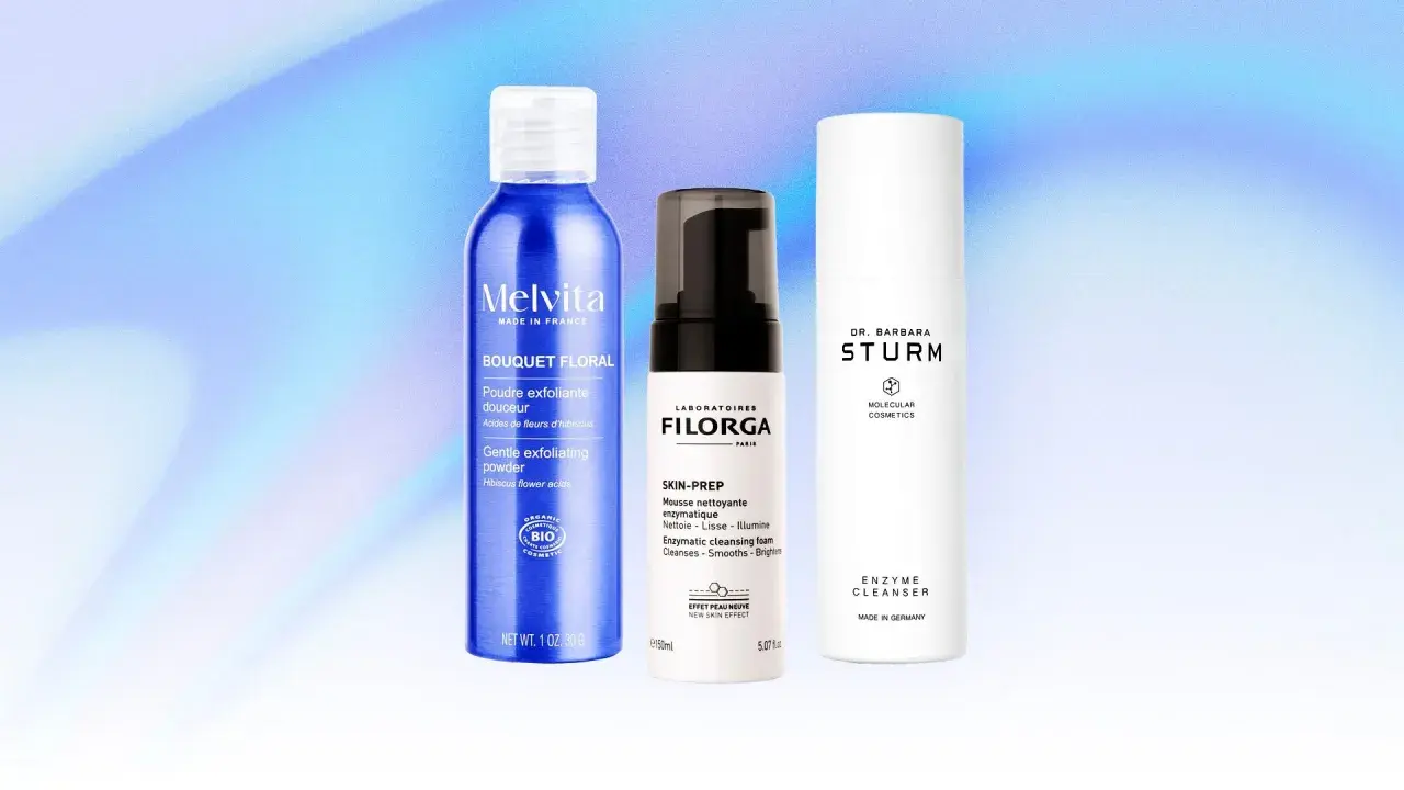 Tre flaconi di prodotti per la cura della pelle, tra cui una polvere esfoliante e due detergenti enzimatici, su sfondo blu sfumato.