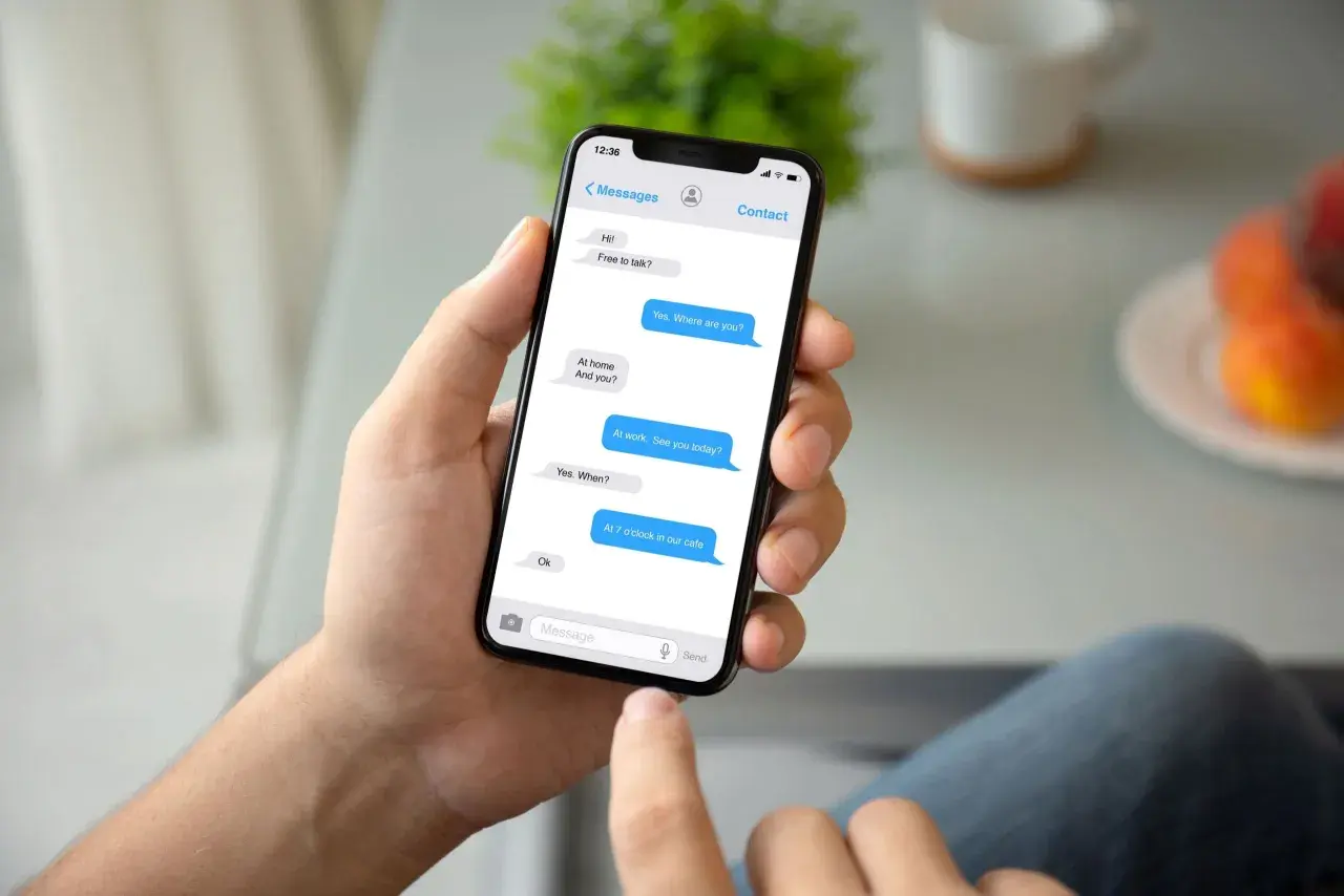 Dłoń trzyma smartfon z widocznym oknem czatu Messenger. Rozmowa dotyczy spotkania. Jak przywrócić wiadomości na Messengerze?
