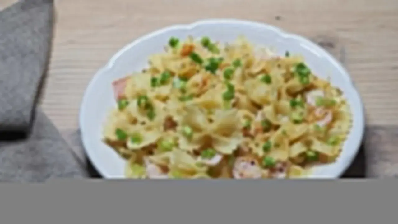 Szybki obiad z makaronem farfalle, szynką i szczypiorkiem, polany kremowym sosem.