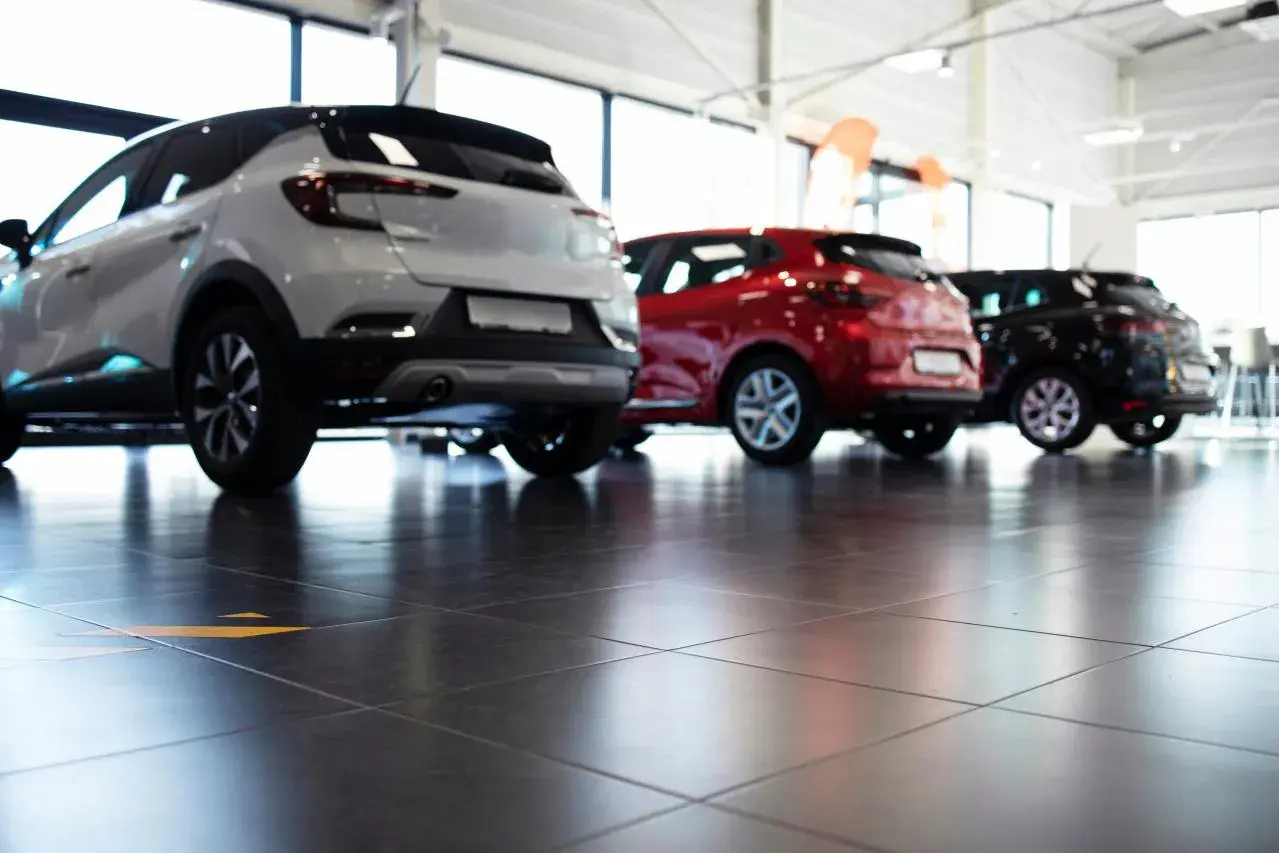 Tre auto, bianca, rossa e nera, in un concessionario. La valutazione autoscout è facilitata dalla vista posteriore dei veicoli.