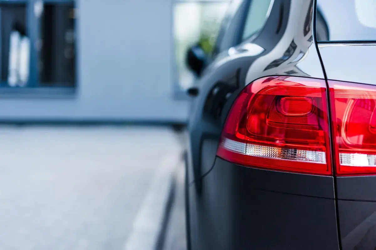 Ciemny samochód, gotowy na uber paczkę. Błyszczący lakier i czerwone światła z tyłu.