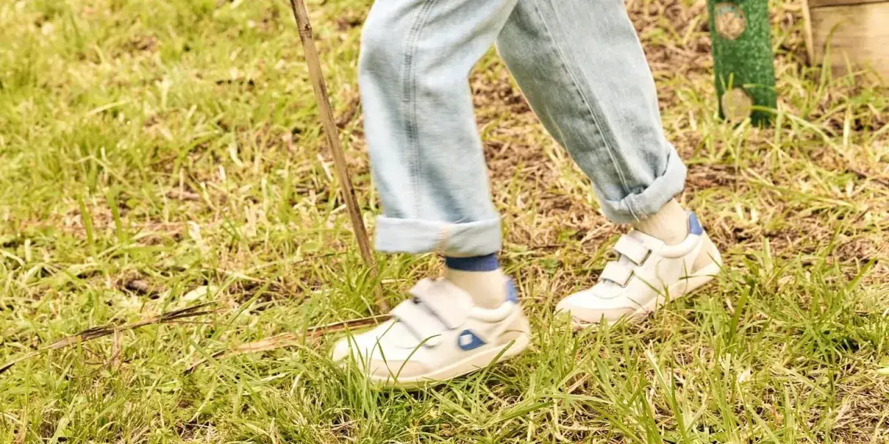 Białe sneakersy na rzepy, idealne na spacer po trawie. To wygodne buty dla aktywnych.