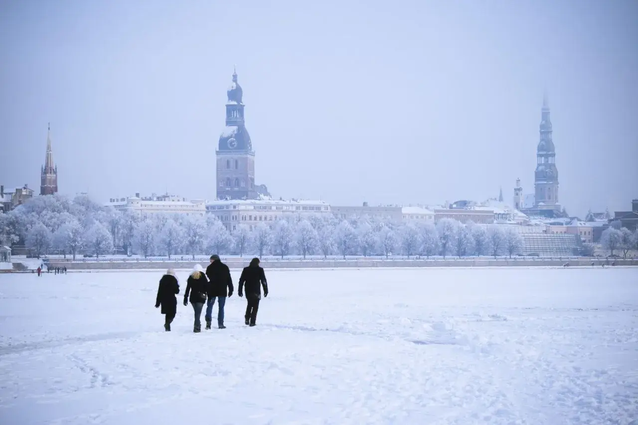 Familie spaziert über zugefrorene Daugava in Riga, Lettland im Winter. Die Stadt mit ihren Türmen ist im Schnee versunken.