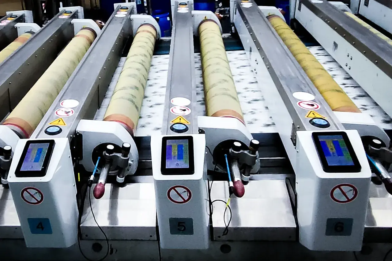 Lignes de machines industrielles pour l'impression rotative, avec des rouleaux et des écrans tactiles.