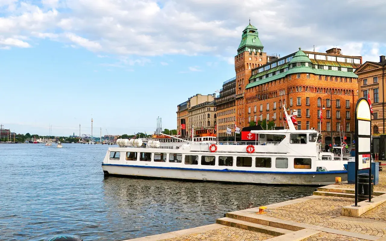 En vit passagerarbåt ligger vid kajen i Stockholm. En båttur här ger fin utsikt över stadens vackra byggnader och vattnet.